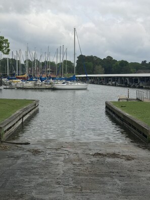 A marina with boats docked, a covered walkway, and a grassy area.