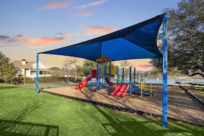 A playground with slides and a covered play area, surrounded by grass and trees. - Reel in Romance ~ Lake Conroe ~ Fish off your balcony.  (Willis)