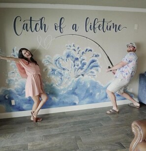A room with a mural featuring a wave and the text "Catch of a lifetime."