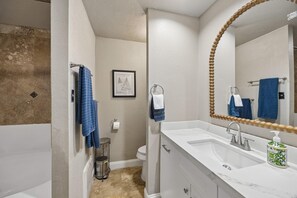 Une salle de bain avec une baignoire, un lavabo avec un miroir et des toilettes.