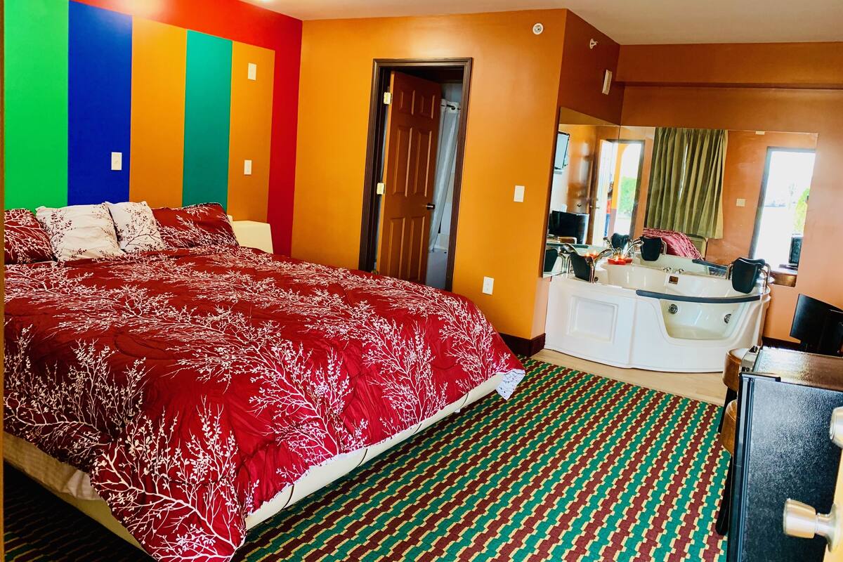 Une chambre d’hôtel avec un grand lit, une salle de bain avec une baignoire et un miroir.