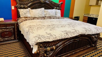 Una cama de madera clásica con intrincados grabados, una colcha estampada y una mesita de noche a juego.