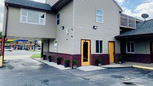 A two-story building with a flat roof, a visible entrance, and a satellite dish on the roof. - Motor City Inn & Suites (Melvindale)