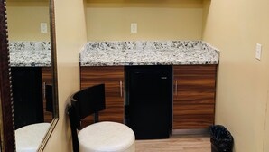 A compact bathroom with a wooden vanity, a black sink, and a mirror. - Motor City Inn & Suites (Melvindale)