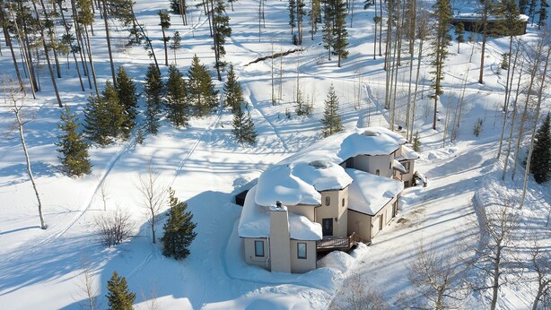 A snow-covered lodge with multiple buildings, surrounded by a forest.