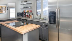 A modern kitchen with a stainless steel refrigerator, a built-in oven, and a wooden island.