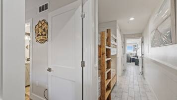 A hallway with a white door, a wooden shelf unit, and a framed artwork on the wall.