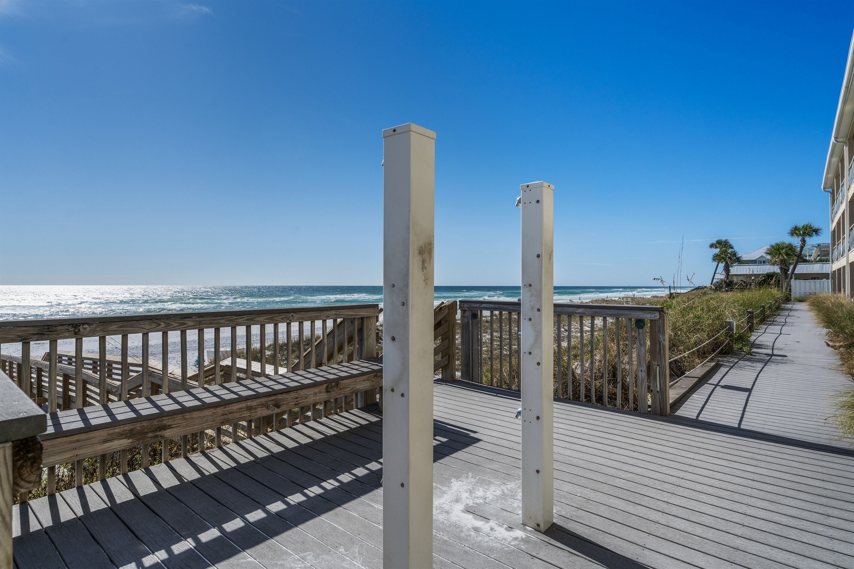 A wooden boardwalk leading to a beach with a clear view of the ocean.