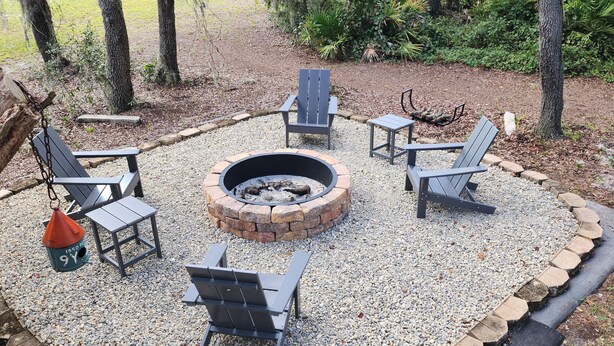 An outdoor seating area with a fire pit, surrounded by Adirondack chairs and a bird feeder. - 10 Acres  Farm House (Frostproof)