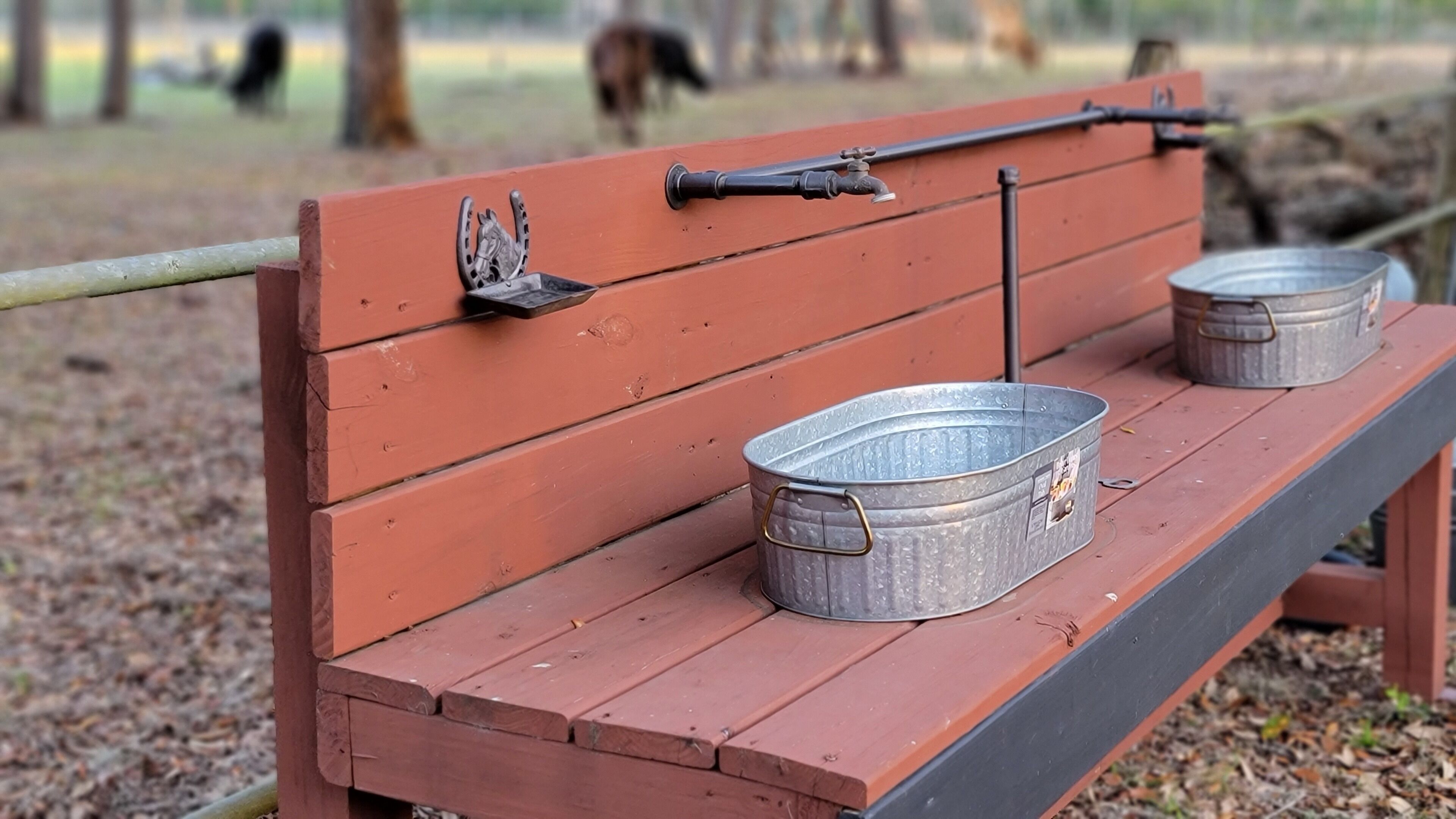A wooden bench with metal buckets and a horse head ornament.