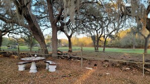 A park with a picnic table and benches, surrounded by trees and a fence. - 10 Acres  Farm House (Frostproof)