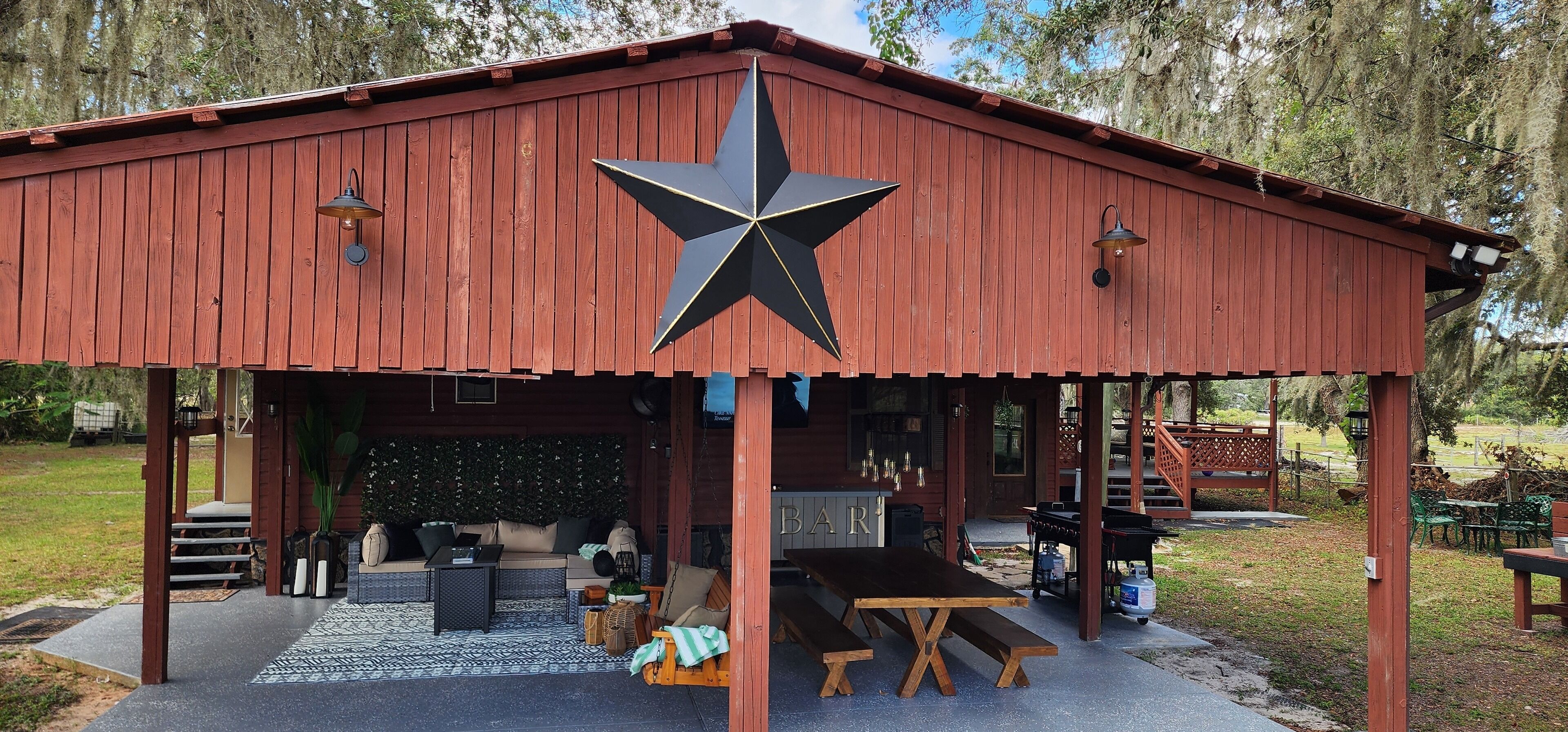 A rustic wooden building with a large star decoration, a covered outdoor seating area, and a bar.