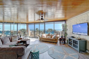A spacious living room with a large TV, comfortable seating, and a view of the ocean. - Mayan Princess 314 | Panoramic Ocean-Pool Views (Port Aransas)