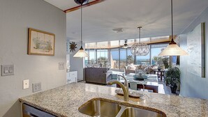 Una cocina con encimeras de granito, pileta de acero inoxidable e iluminación colgante.