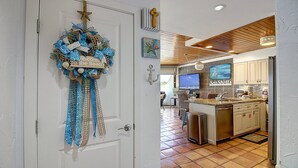 A kitchen with a wooden ceiling, a large island, and a television above the counter. - Easy pool and beach access | MP 114 (Port Aransas)