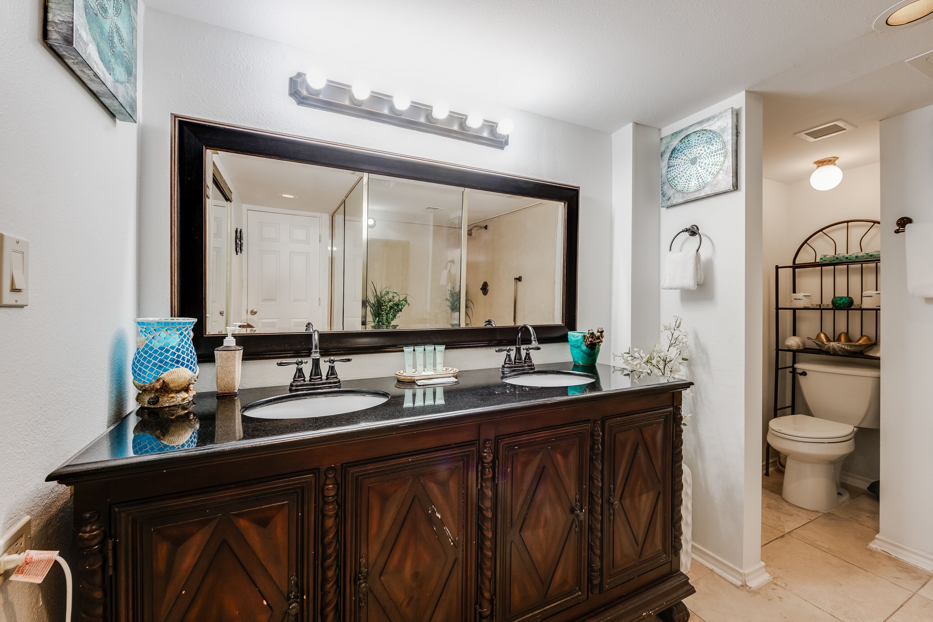 A bathroom with a double sink vanity, a large mirror, and a toilet.