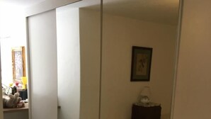 Une chambre à coucher avec un lit, une table de chevet, un miroir et une armoire.