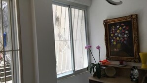 Une pièce dotée d’une grande fenêtre, d’un tableau encadré et d’une commode sur laquelle sont disposés divers objets.
