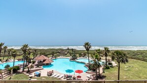 A resort with a large pool, palm trees, and a view of the ocean.