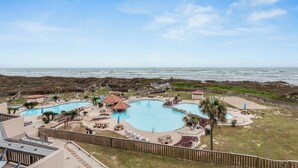 Un resort con una gran piscina, mobiliario exterior y vistas al océano.