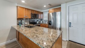 Una cocina moderna con encimeras de granito, gabinetes de madera y electrodomésticos de acero inoxidable, además de un horno empotrado.