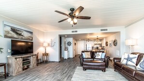 A spacious living room with a large flat-screen TV, a leather sofa, and a wooden entertainment unit.