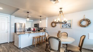 A modern kitchen with white cabinets, stainless steel appliances, and a central island with stools.