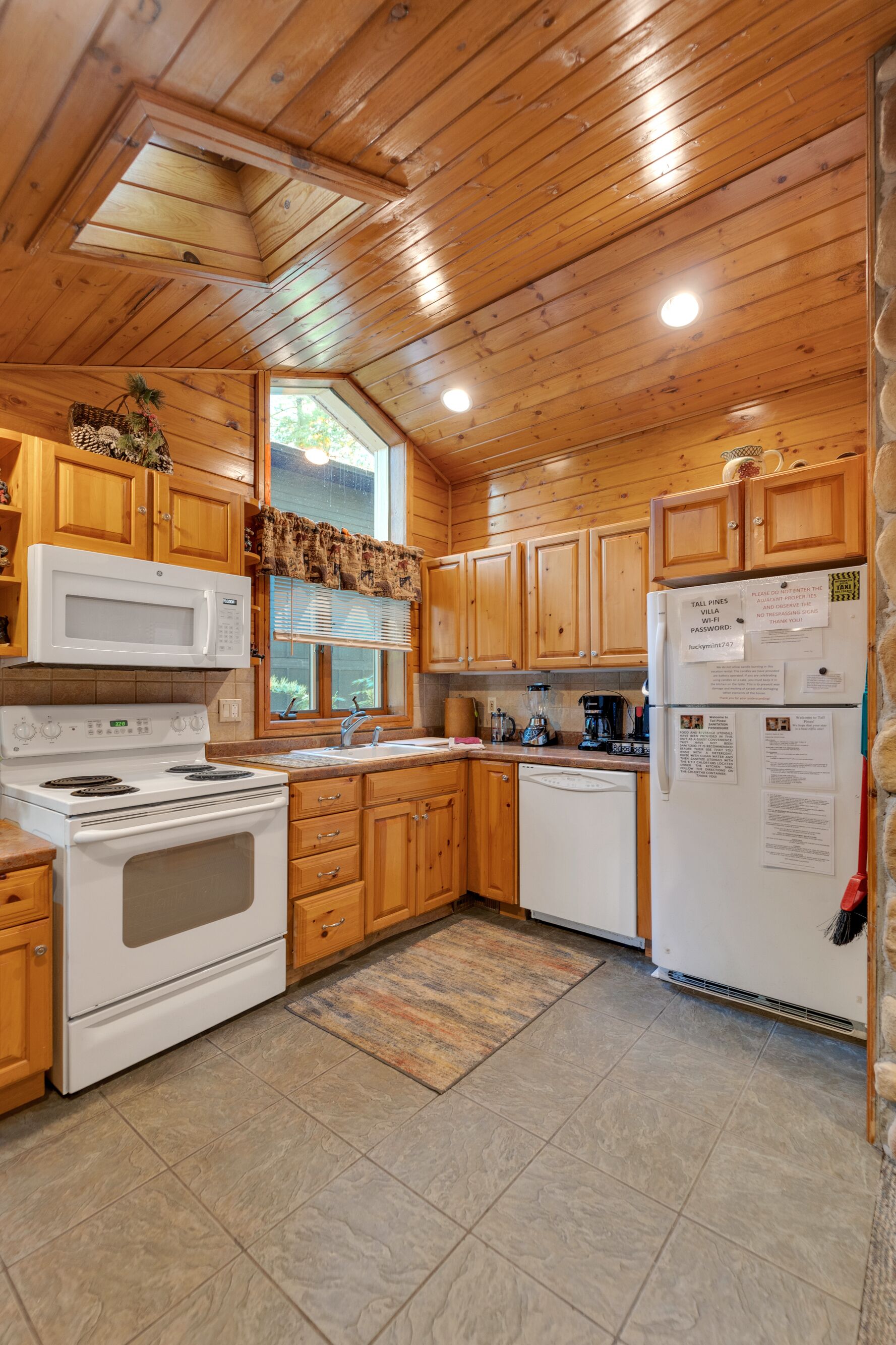 A kitchen with wooden cabinets, a white stove, a microwave, and a refrigerator.