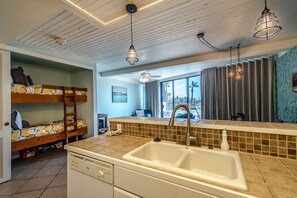 A modern kitchen with a large sink, a dishwasher, and a dining area with a view of the outdoors. - Sassy Seagull @ The Mayan Princess (Port Aransas)