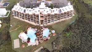 An aerial view of a hotel with multiple balconies, a swimming pool, and a landscaped area with palm trees. - Sassy Seagull @ The Mayan Princess (Port Aransas)