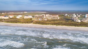 A coastal hotel with multiple buildings, a beach, and ocean waves. - Sassy Seagull @ The Mayan Princess (Port Aransas)