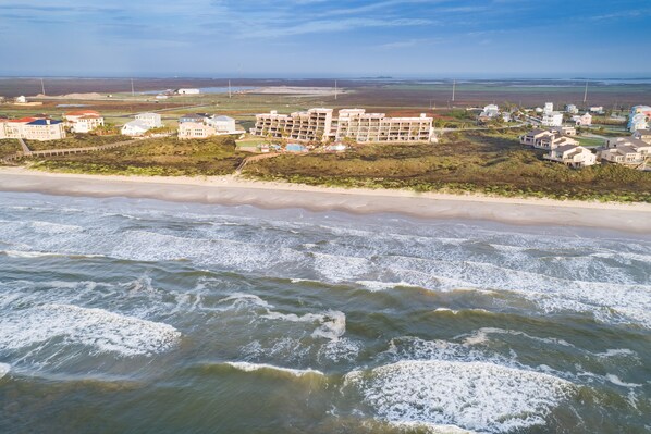 A coastal hotel with multiple buildings, a beach, and ocean waves. - Sassy Seagull @ The Mayan Princess (Port Aransas)