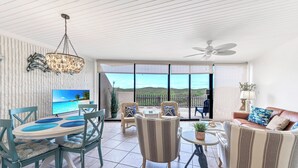 A spacious living area with a dining table, chairs, a sofa, and a TV. - Poolside views | Private access to beach | Beachfront | MP103 (Port Aransas)