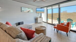 A modern living room with a large TV, comfortable seating, and a view of the beach. - A Beachy Dream MP118 | Resort Pools | Private Boardwalk (Port Aransas)