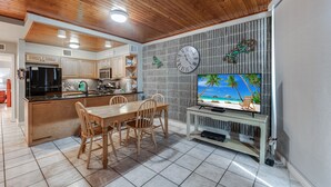 Une cuisine moderne avec des meubles en bois, un réfrigérateur noir et un coin repas comprenant une table et des chaises en bois.