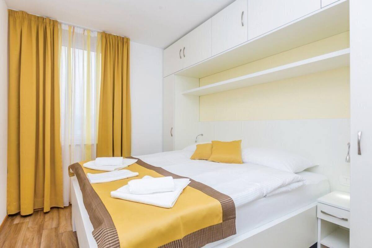 A hotel room with a bed, a nightstand, a wardrobe, and a window with curtains.