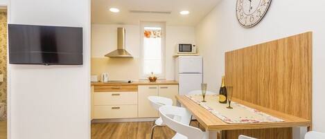 A compact kitchen with a TV, microwave, and wooden panel wall.