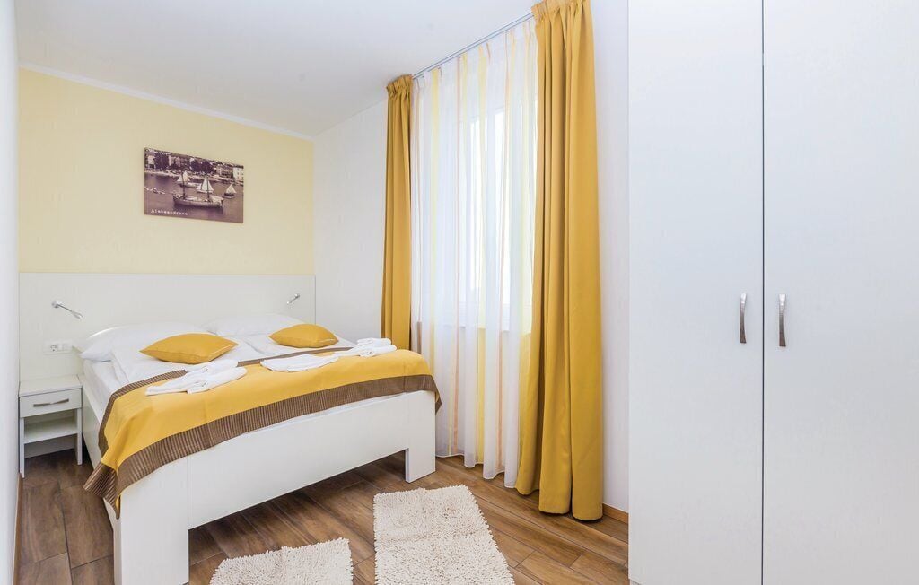 A bedroom with a bed, a nightstand, a wardrobe, and a window with curtains.