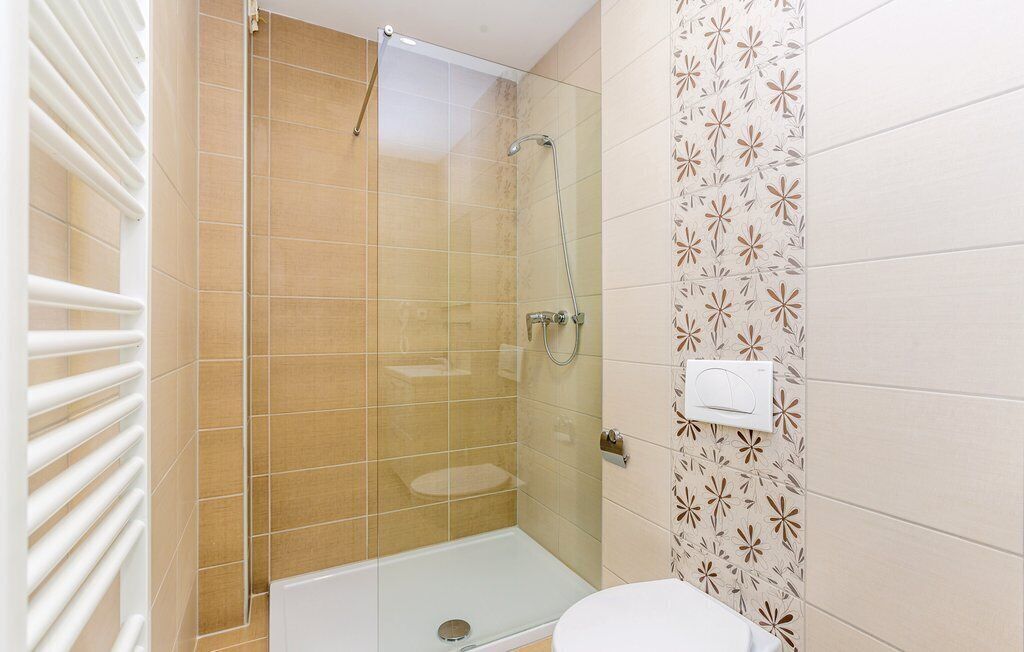 Un baño con ducha envuelta en vidrio, inodoro y toallero de pared.