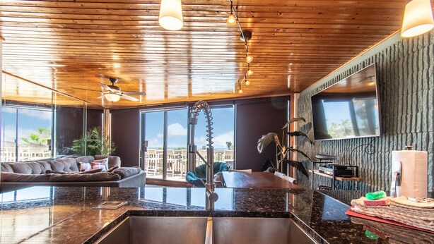 A modern kitchen with a large island, stainless steel sink, and a view of the city. - Live Your Best Beach Life @ Mayan Princess 211 (Port Aransas)