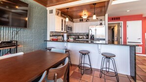 A modern kitchen with white cabinets, a stainless steel refrigerator, and a wooden ceiling. - Live Your Best Beach Life @ Mayan Princess 211 (Port Aransas)