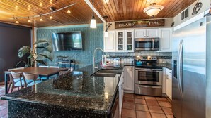 A modern kitchen with granite countertops, stainless steel appliances, and a wooden ceiling. - Live Your Best Beach Life @ Mayan Princess 211 (Port Aransas)