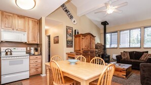 Een gezellige woonkamer met een open haard, een eethoek met houten meubels, en een keuken met moderne apparatuur.