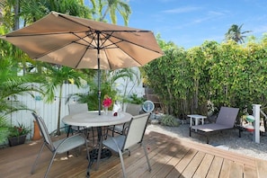 A patio with a round table, chairs, and a large umbrella.