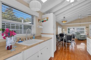 A modern kitchen with a sink, countertop, and a dining area with chairs and a table. - 5 minutes to Dolphin Research Center
Family and Pet-Friendly! (Marathon)