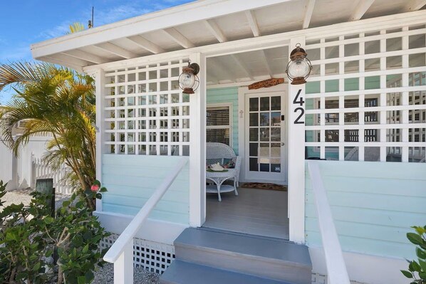 A white building with a porch, a number '42' sign, and a wicker chair.