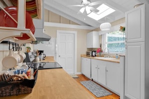 A modern kitchen with white cabinets, a black countertop, and a ceiling fan.