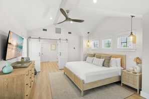A bedroom with a bed, a ceiling fan, a TV, and a window. - Take Me Away - Stylish Coastal Escape with Pool Near Beach and Trolley (Holmes Beach)