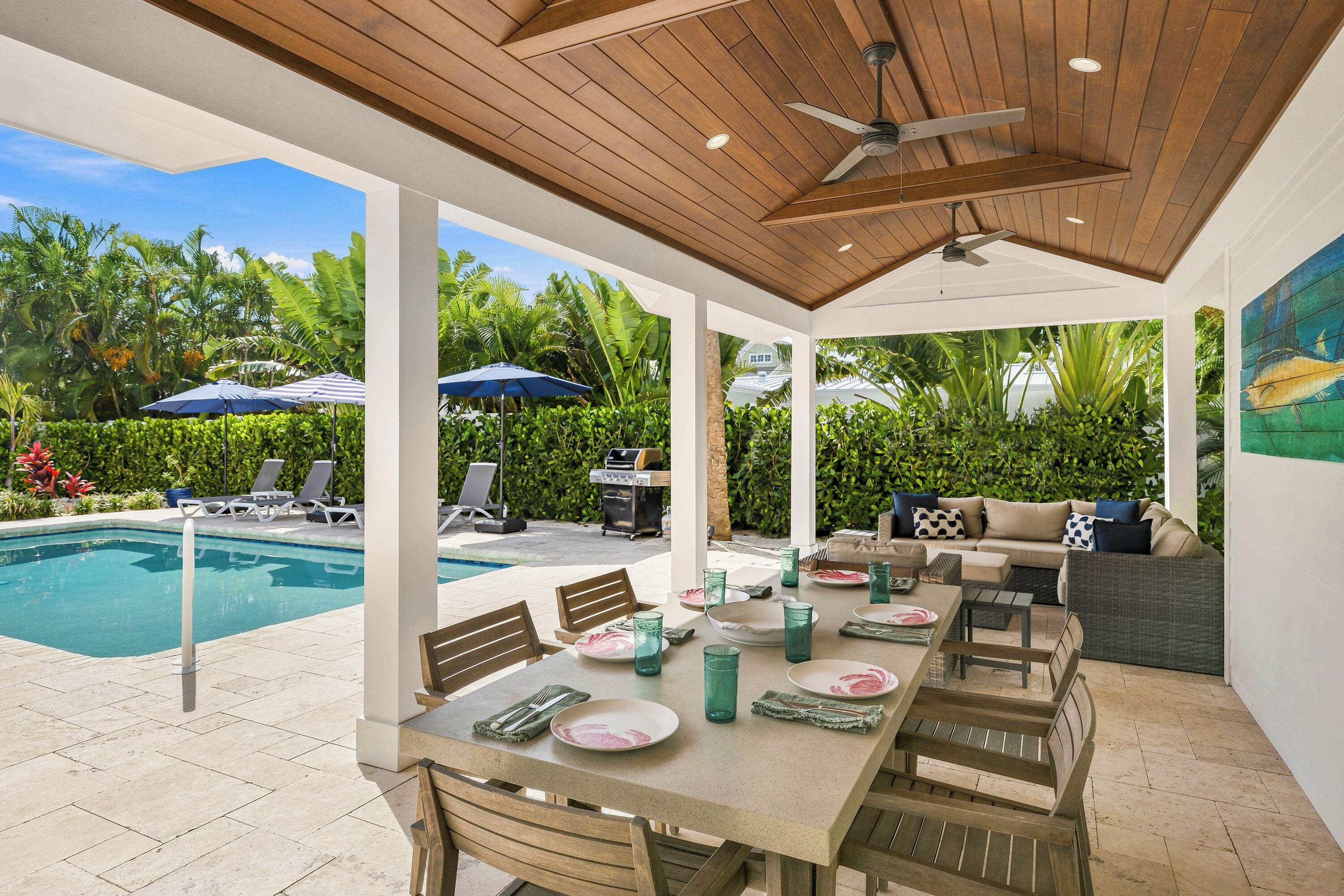 Un patio exterior con piscina, zona de comedor y sillones de descanso.