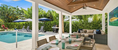 An outdoor patio with a pool, dining area, and lounge chairs.